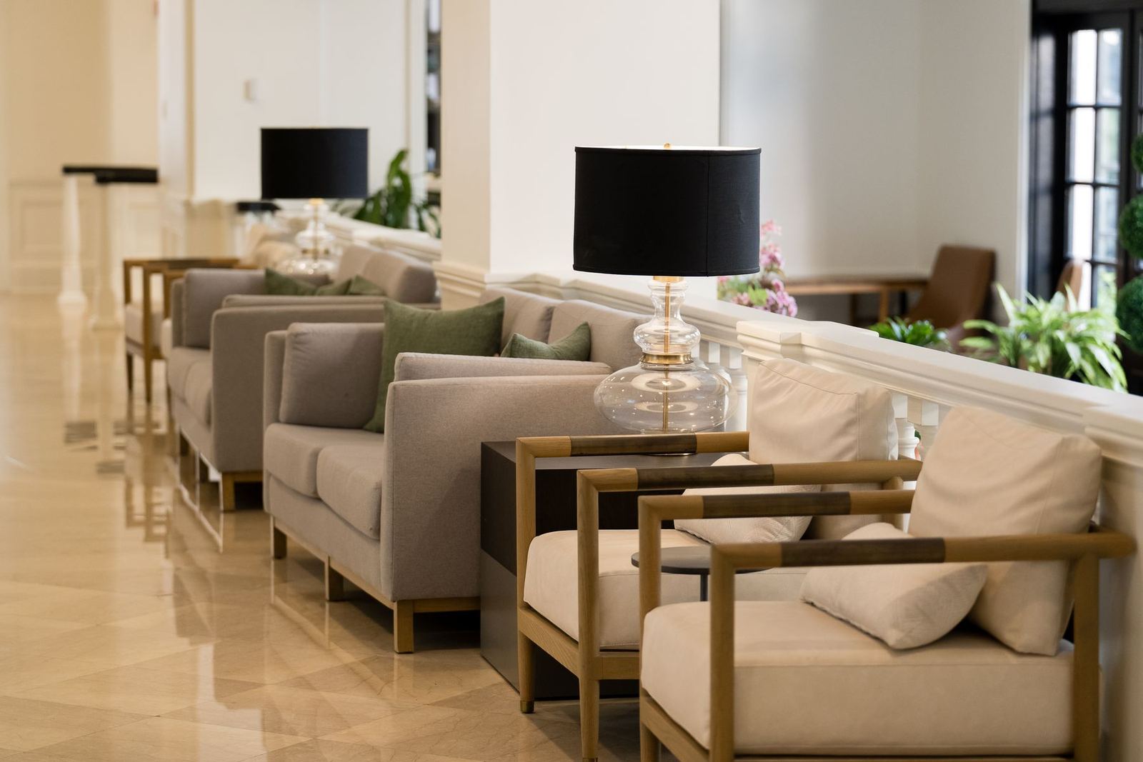 A quiet hotel lobby with lamps and linen seating